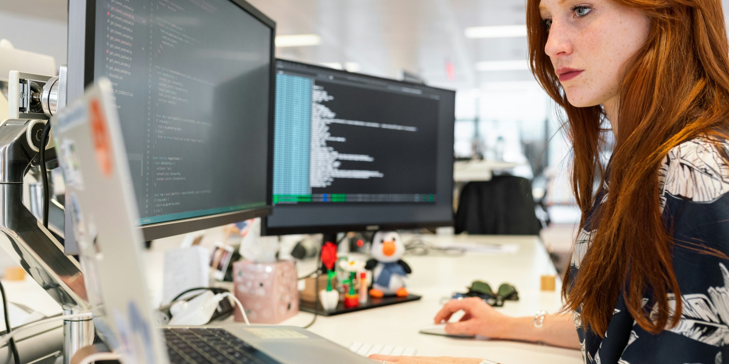 An engineer working through code on a two-screen workstation