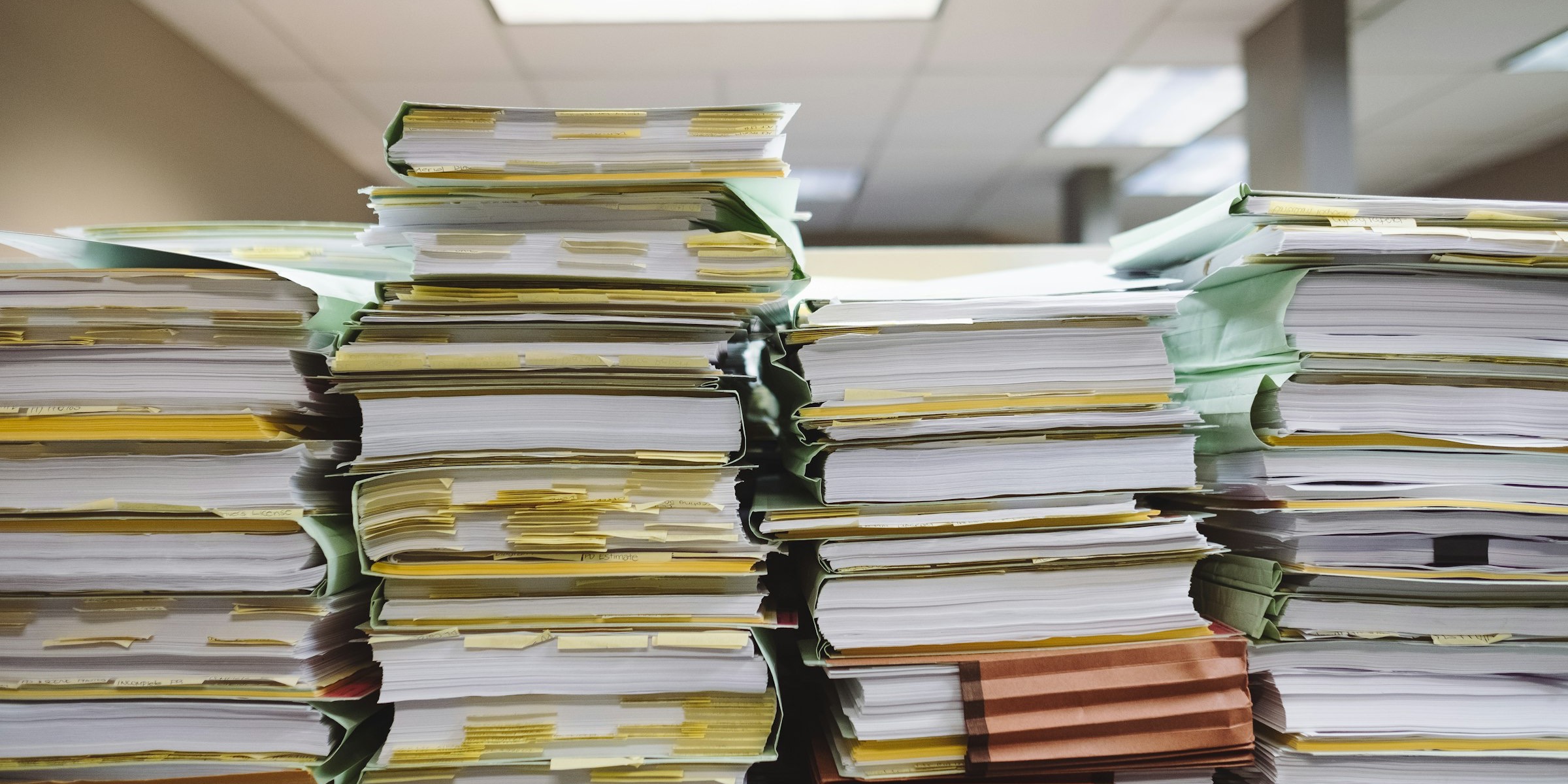 Stacked paper documents and file folders in loose piles