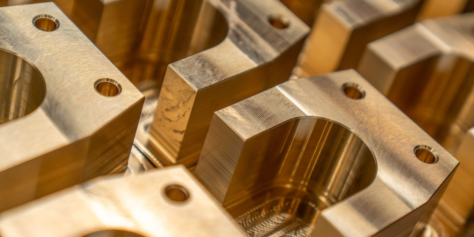 Rows of machined brass blocks, each with a milled pocket and two bolt holes