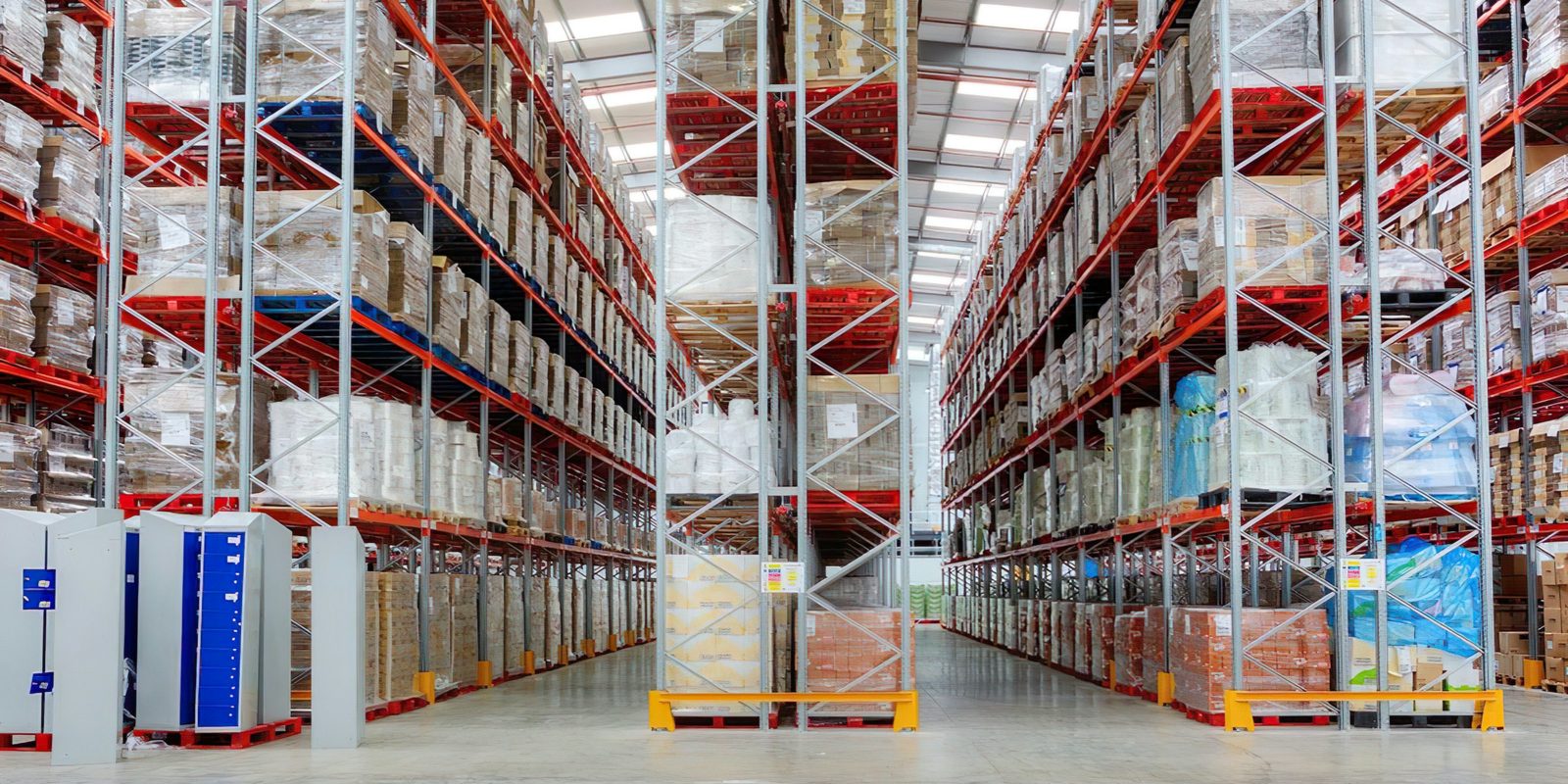 Tall pallet racks full of boxed and wrapped goods line the aisles of a bright distribution centre