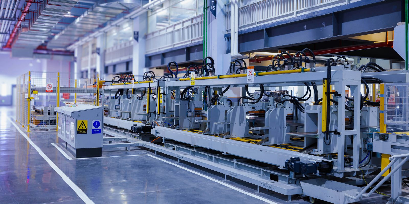 A bright, automated forming line with guarded stations and cable carriers on a clean plant floor