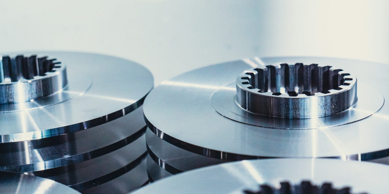 Machined steel discs with splined centres, stacked in a bright workshop