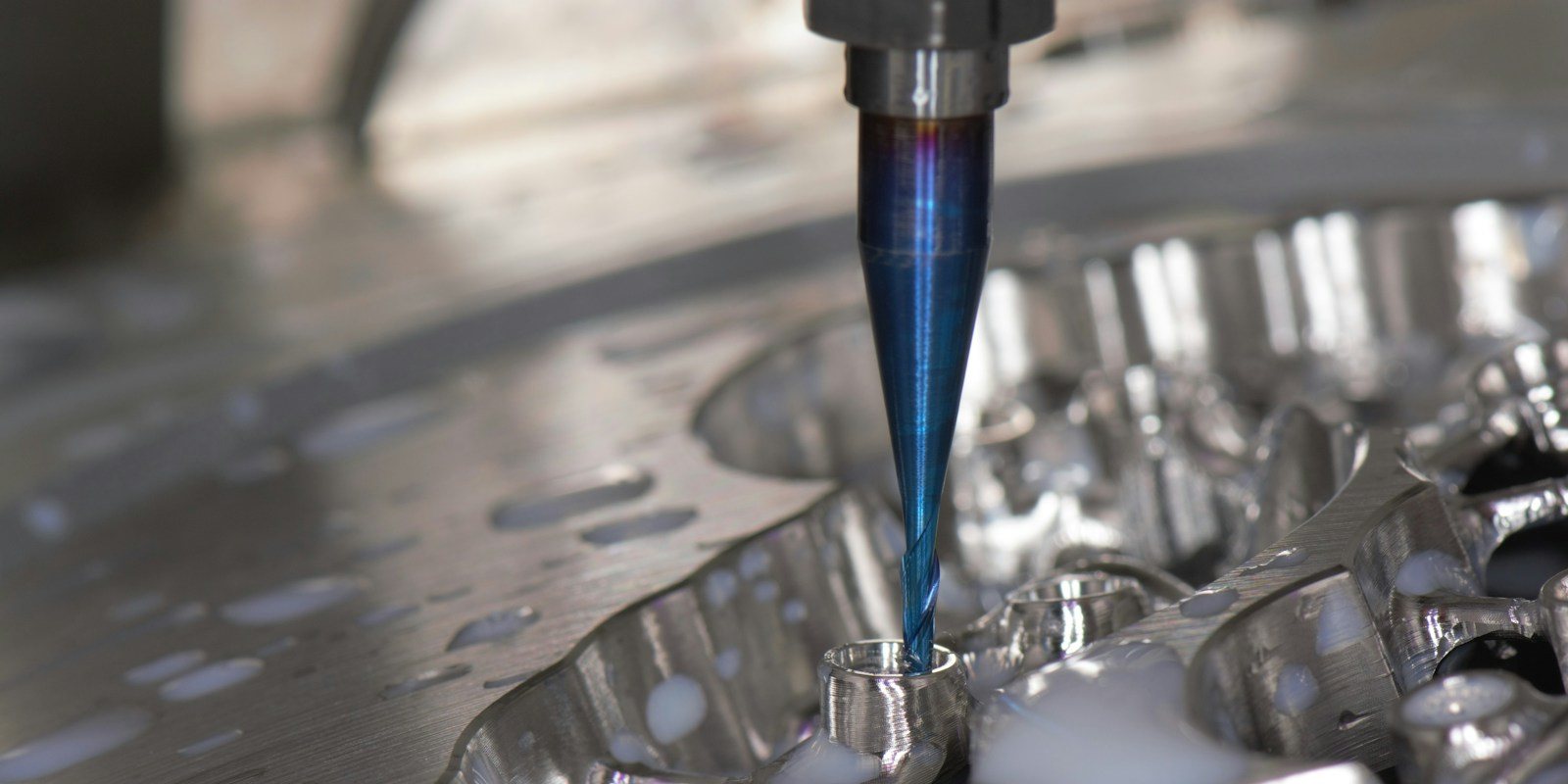A milling cutter shaping an aluminium part inside a CNC machining centre