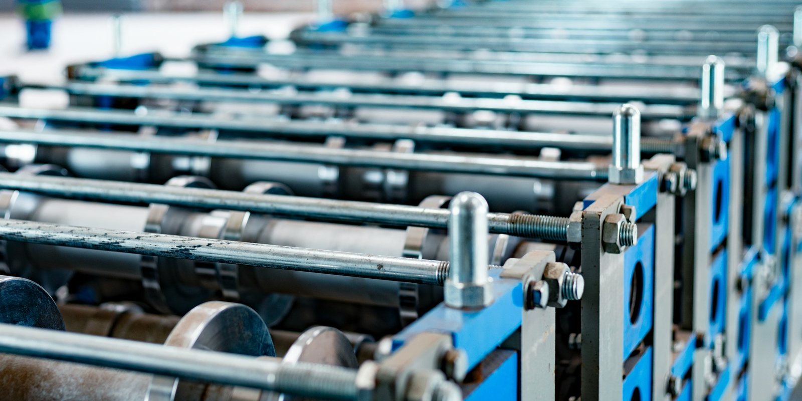 Rows of steel forming rolls on blue stands along a long production machine