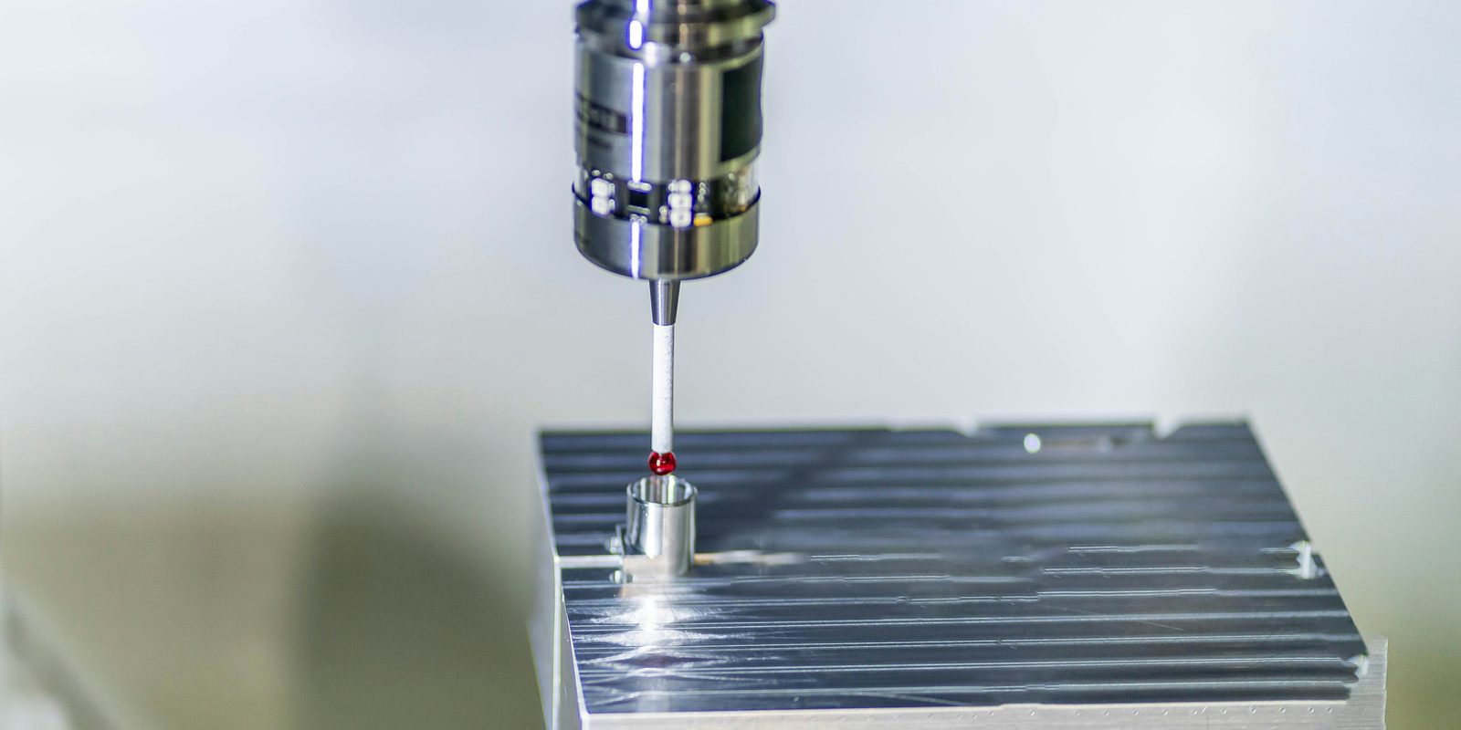 CMM touch probe with a ruby stylus tip measures a bore on a machined aluminium block