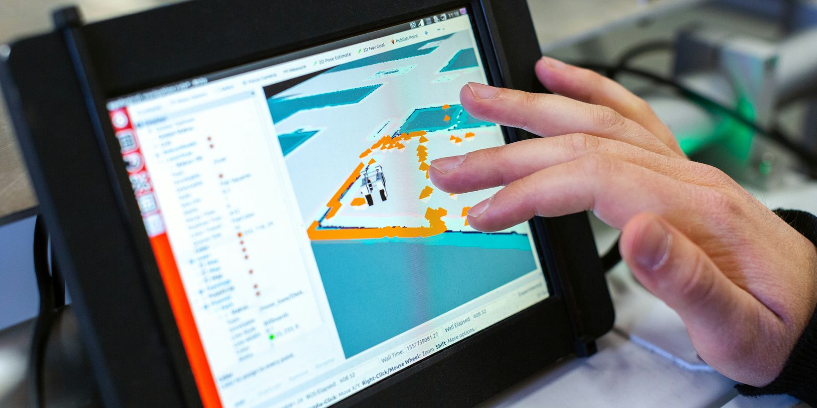 A hand works a machine-side touchscreen that shows a cutting job layout