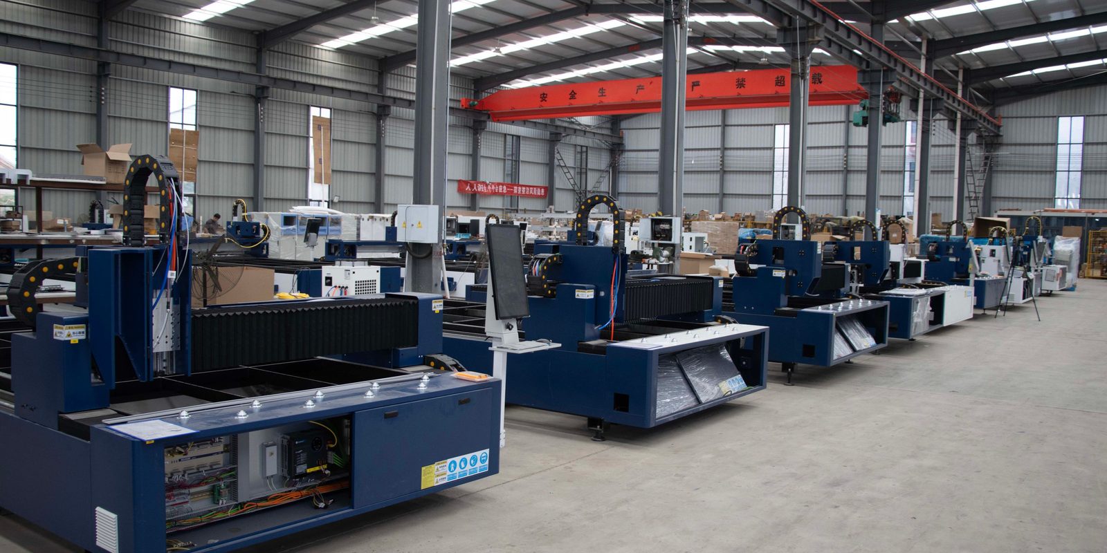 A row of new laser cutting machines lined up on the floor of a large, bright factory hall