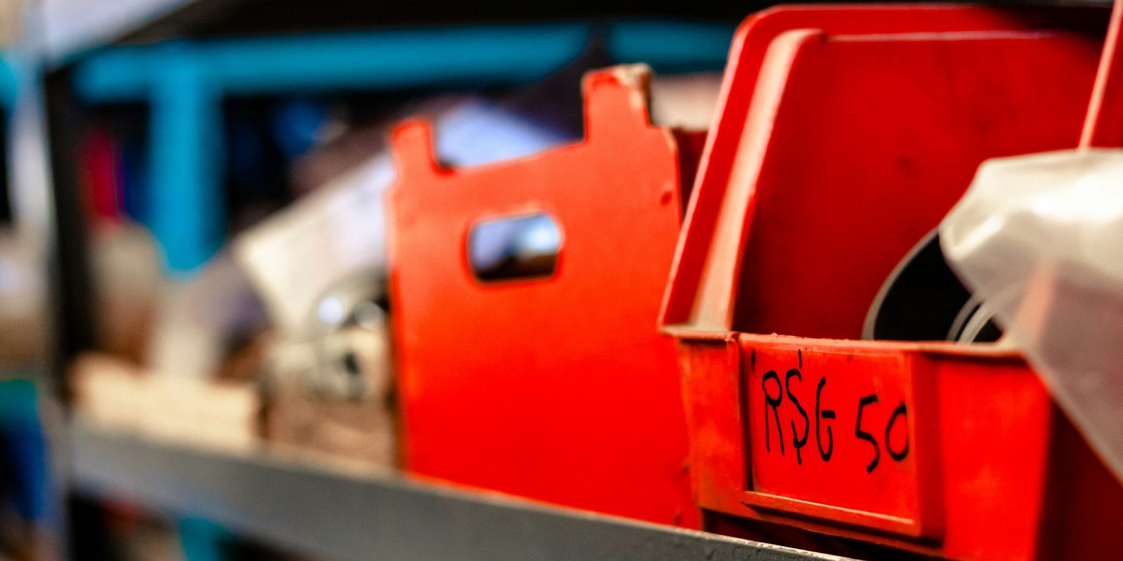 Red plastic parts bins on a steel shelf, one bin marked RSG 50 by hand
