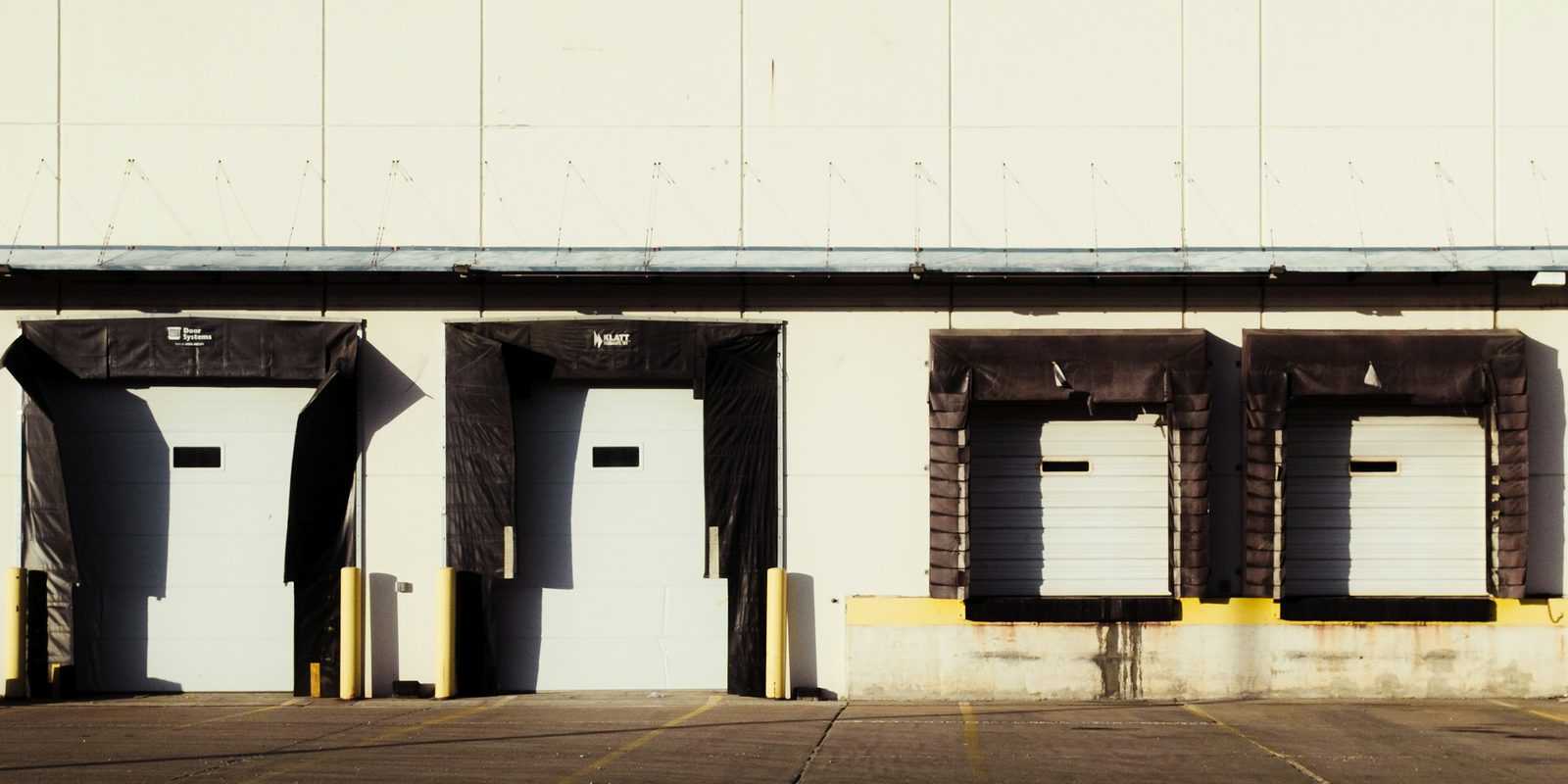 Four loading dock doors with dock seals along the white wall of a distribution building