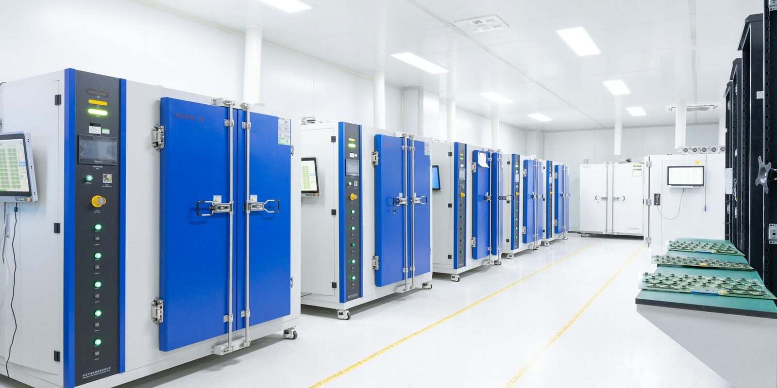 A row of blue and white environmental test chambers in a bright, white test laboratory
