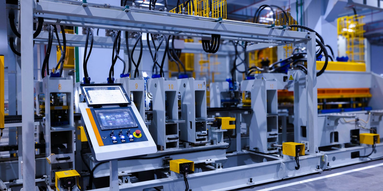 An operator touchscreen and selector switches on a bright, automated forming line