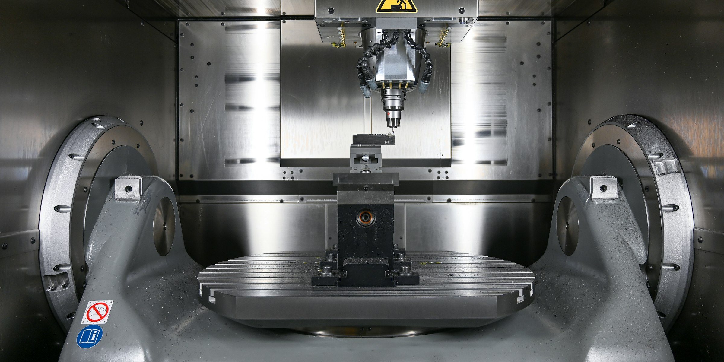 The interior of a modern five-axis machining centre, spindle loaded over a trunnion table