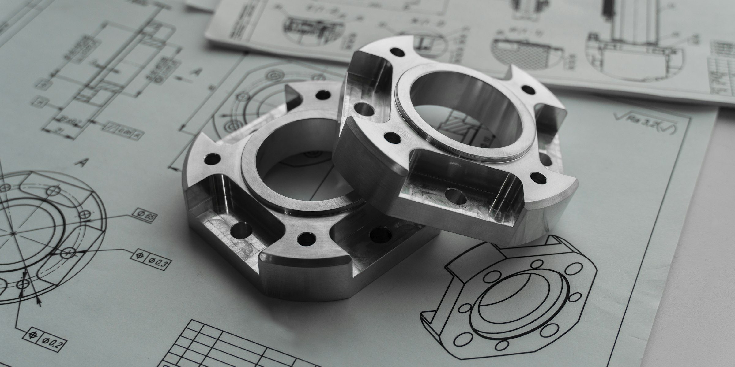 Two machined flanges resting on dimensioned engineering drawings